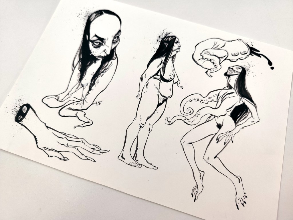 Photo of hand-drawn black-and-white ink line art on paper showing surreal horror figures: a crouching creature, a reclining woman with tentacle forms, and a severed clawed hand.